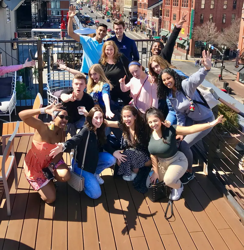 Group of friends celebrating on a rooftop over Broadway in Nashville