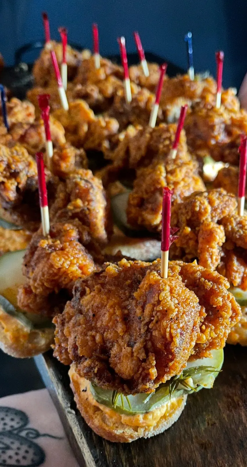 Nashville hot chicken sliders with pickles on a serving board